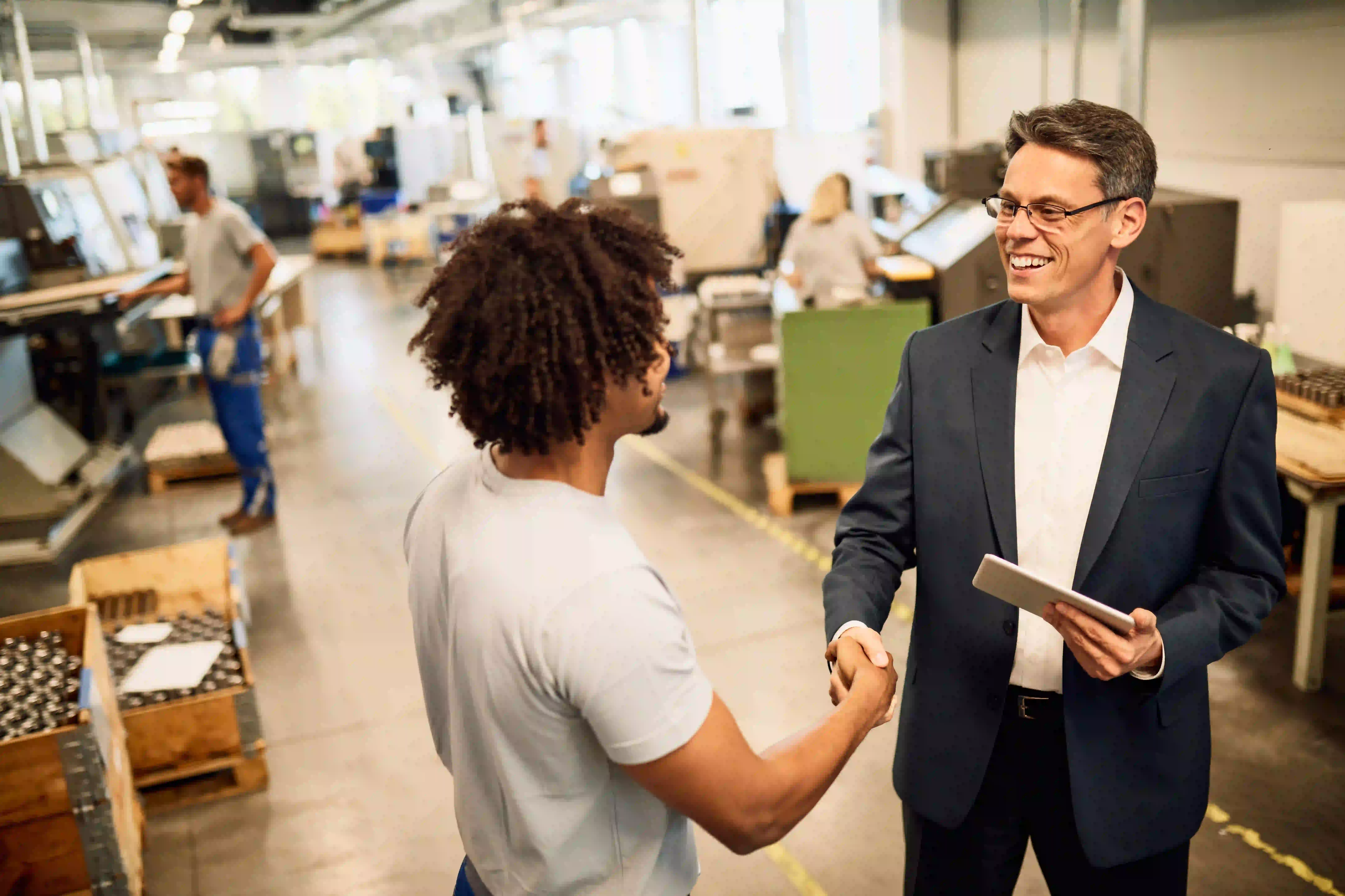 A manager and a workshop employee shake hands